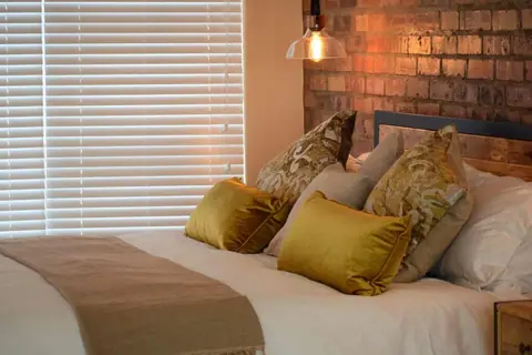 King bed with gold cushions against an exposed brick wall