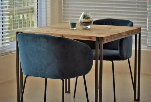 Table for two with velvet chairs by a shuttered window