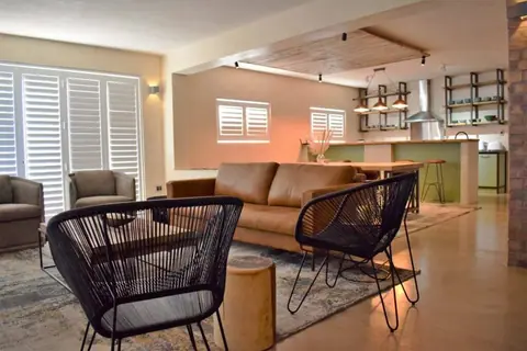 Open-plan lounge with a leather sofa and woven chairs