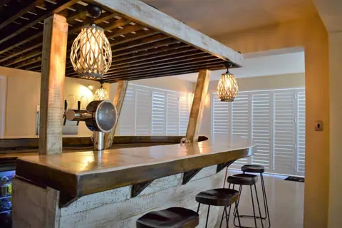 The Zoe boat-bar with bar stools and woven pendant lamps
