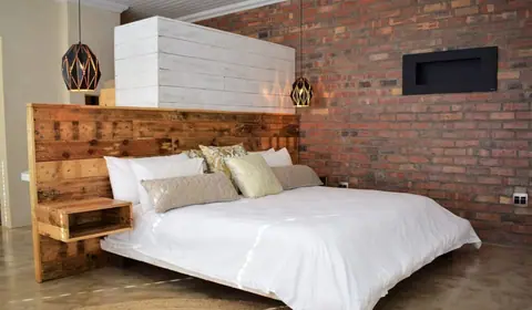 King bed with a reclaimed-wood headboard and brick wall