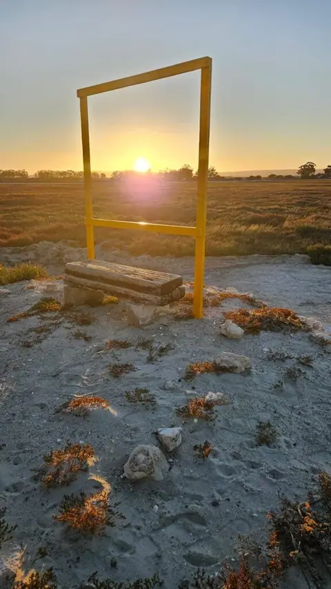 Yellow frame sculpture on the beach at sunrise